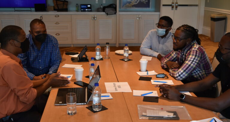 Caribbean professionals sitting at a table with water and computers