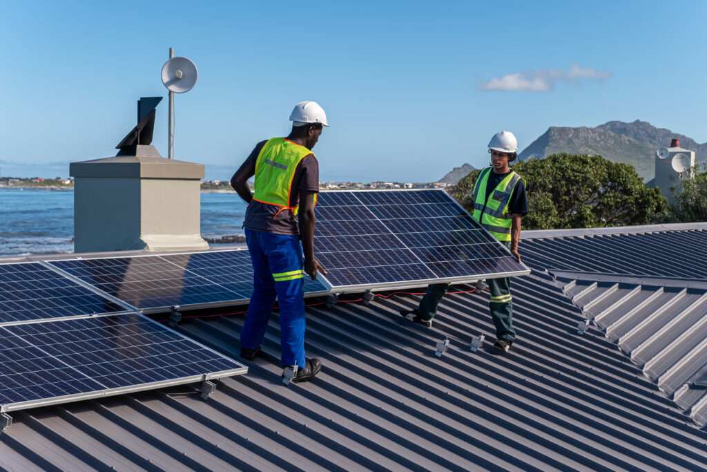 Technicians install solar panels on a roof