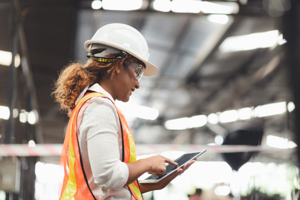 woman in hard hat referencing tablet